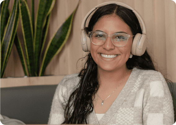 Estudiante de la Universidad de América sonriendo con audífonos mientras usa plataformas digitales institucionales.