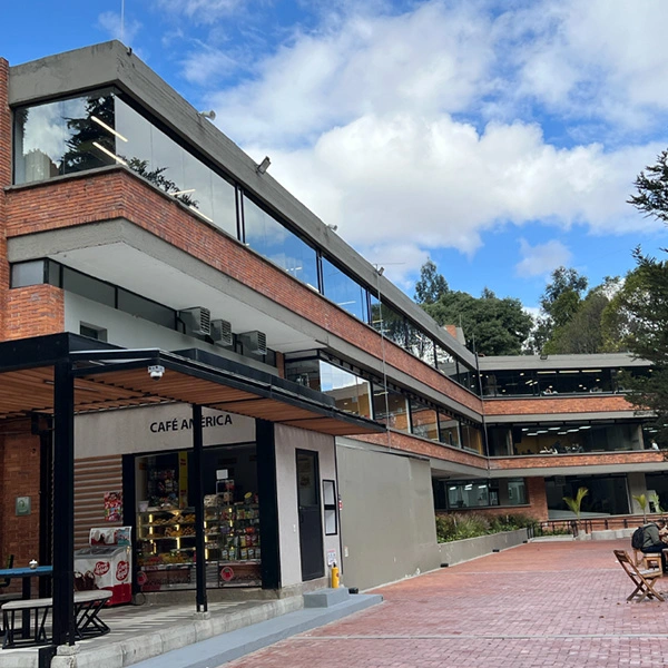 Fachada principal de la Universidad de América en Bogotá con zonas verdes y cafetería.